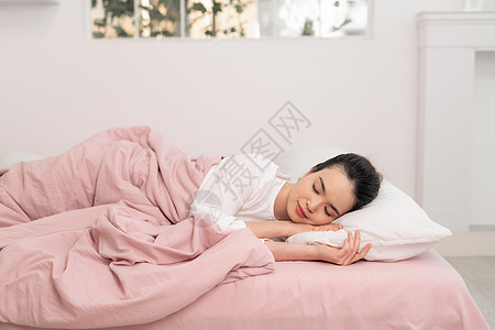 快乐的亚洲年轻美容女性清晨在床上睡觉和微笑图片