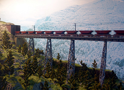 一辆货运火车在穿越山谷的铁路桥上行驶 该铁路桥横跨河谷石头蓝色金属景观地标运输建筑学车站建筑速度图片