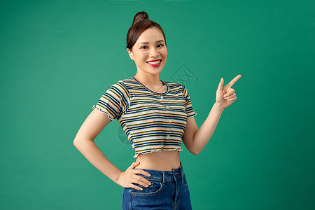 身穿便衣的快乐亚洲女青年 用她的手指对着绿色背景指着她女性女士成人女孩喜悦头发图片