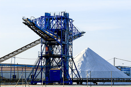 蓝色机器盐厂内机器旁边的盐山背景