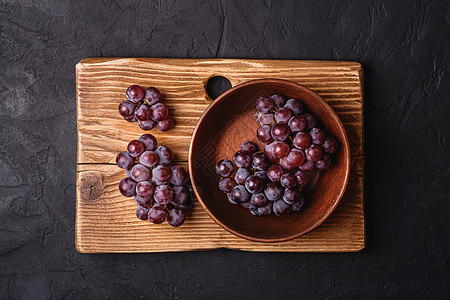 棕色木头碗中新鲜成熟的葡萄莓和黑石底面 顶层风景的切割板图片