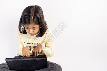 可爱的小女孩在用笔记本和耳机技术孩子们学生爱好网络知识专注女孩们家庭作业学习图片