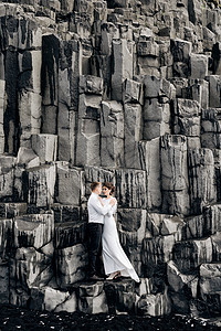新娘和新郎正拥抱在Vik的黑沙滩上 目的地冰岛的婚礼 (见 冰河之旅 )图片