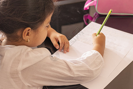 女孩在一张小桌子上写字女学生蜡笔知识字母个性写作学校女孩们课堂考试图片