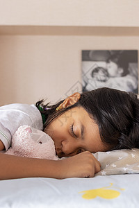 小女孩睡在她房间里的床上睡觉时间头发孩子卧室午睡玩具枕头女性寝具生活图片