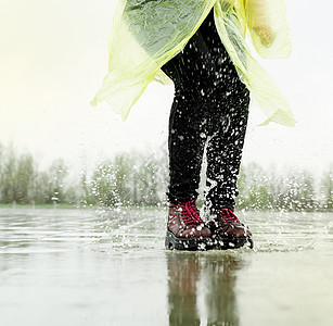 女人在雨中玩耍 在水坑里跳飞溅城市女士天气赛跑者运动员闲暇行动沥青女孩图片