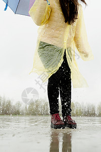 女人在雨中玩耍 在水坑里跳沥青女孩行动训练闲暇跑步城市天气速度赛跑者图片