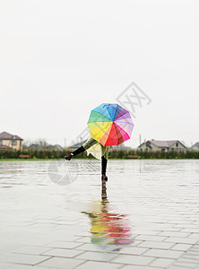 女人拿着多彩的雨伞在雨中跳舞图片