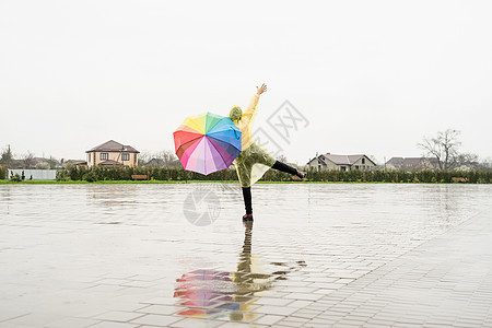 美丽的黑褐色女人 在雨中舞着多彩的雨伞微笑成人季节女性喜悦公园快乐天气乐趣彩虹图片