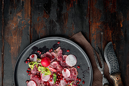 配有葡萄酒醋的新鲜卡帕西奥沙拉 配有Radish和garnet 在盘子上 用旧黑木板桌底 顶层平面 可复制文字空间图片