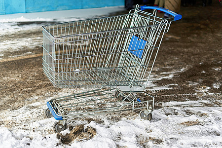 来自超市的金属购物小车 在户外雪和泥土中站立图片