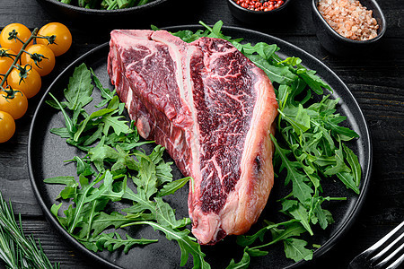 煮肉背景 生老牛肉T骨牛排 配有香料和烧烤草药 黑木制餐桌背景背景图片