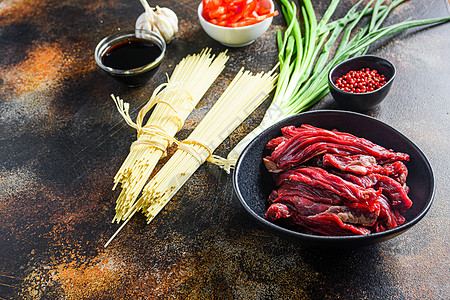 煮炒中国面条菜和黑碗牛肉的原料 在老旧的生锈桌子上 侧边看图片