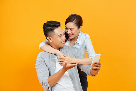 分享智能手机观看媒体内容的有趣的情侣或婚姻背景图片