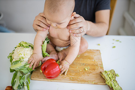 父亲亲爱地把他的女婴抱在桌子上男人蔬菜喜悦女性小姑娘营养男性厨房食物菜花图片