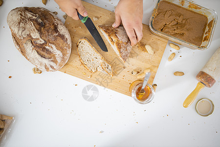 女性用手在切割板上切面包小麦小吃美食容器木辊坚果营养食物蜂蜜花生图片