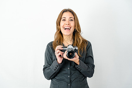 工作室拍摄的微笑快乐的年轻女子拿着旧的老式相机看着摄影师在白色背景上寻找复制空间 对影像的热情和经典摄影史的概念图片