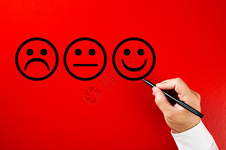 男性手在红色背景上画一张笑脸素描 客户满意度服务或产品评估概念图片