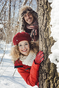 在雪中玩耍的情侣 躲在树干后面季节手套喜悦夫妻森林晴天公园朋友们乐趣下雪图片