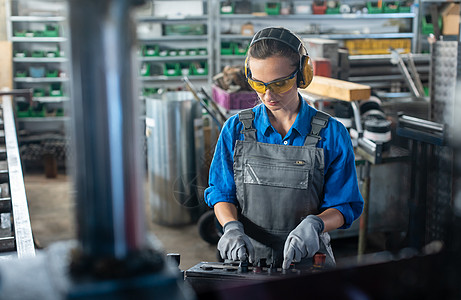 在金属车间或工厂操作机床的女工蓝领锁匠解放蓝色职场生产护耳机锯手套机械图片
