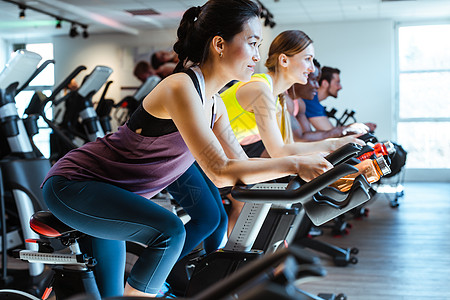 亚裔女人和朋友在健身房的健身自行车上纺纱体操女士乐趣运动朋友们训练团体男人中心图片