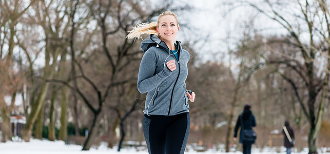 女人在冬天的公园里走过一条路慢跑鞋女孩微笑乐趣喜悦耐力运动训练闲暇慢跑装图片
