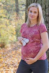 年轻孕妇展示婴儿靴子的年青孕妇图片