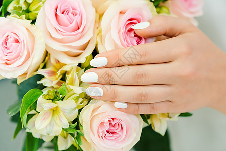 在玫瑰花上修白美甲的年轻女子的指甲沙龙女士护理玫瑰工作室客厅白色美甲店保养花朵背景图片