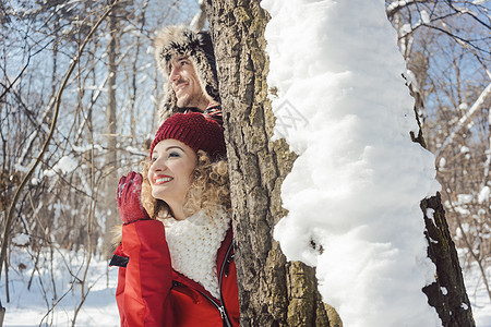 躲在雪中树干后面的玩偶情侣游戏女士季节快乐夫妻晴天冬装乐趣幸福丈夫图片