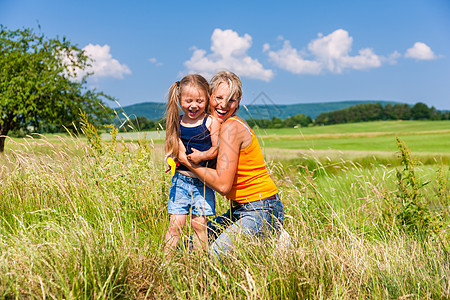 草原上的孩子夏月在草原上的母亲和女儿青年孩子绿色女士阳光幸福太阳阳光照射父母女孩背景