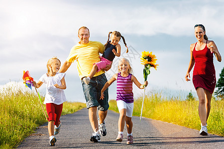 家庭在夏天奔下山丘蓝色国家孩子太阳跑步小路夫妻父母绿色女孩图片