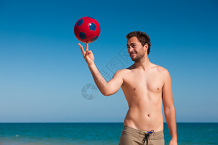 在沙滩上的男人 平衡足球球图片