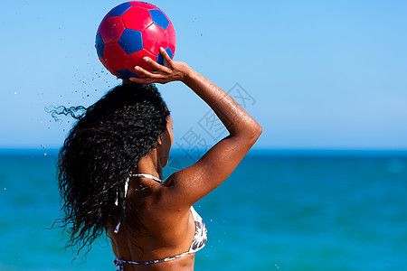 在海滩上玩足球的女人图片