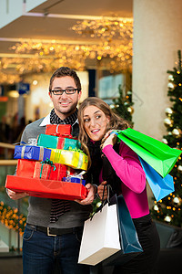 两人在购物中心有圣诞礼物和包袋成人男性乐趣展示女士零售快乐店铺白色喜悦图片