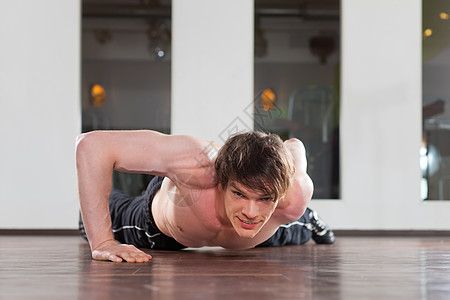在健身房做俯卧撑的人俱乐部中心力量活动身体单臂运动男人手臂健身图片