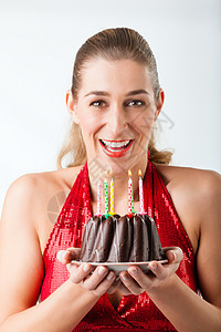 妇女用蛋糕和蜡烛庆祝生日喜悦周年愿望快乐享受展示微笑礼物红色幸福图片
