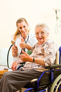 年轻护士和在养老院的女老人社会诊所女性老年轮椅照顾者福利服务测量血压图片