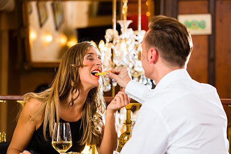 餐厅的一对幸福快乐的情侣吃快餐裙子女士丈夫妻子礼仪白酒男人薯条餐桌枝形图片