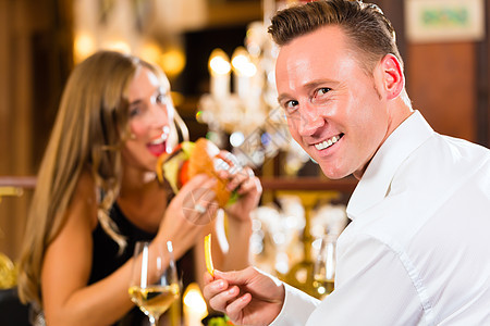 餐厅的一对幸福快乐的情侣吃快餐沙拉夫妻桌子玻璃白酒邀请函庆典女士服装午餐图片