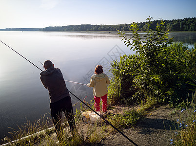 男人和女人在湖里钓鱼运动太阳灌木丛家庭夫妻钓竿渔夫天空倒影女士图片