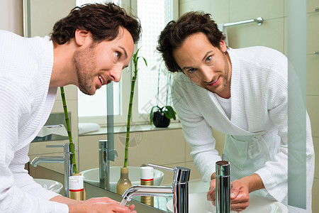 穿浴袍的青年男子 在酒店浴室窗户洗手间脸盆客人龙头洗澡洗涤浴衣厕所毛巾图片