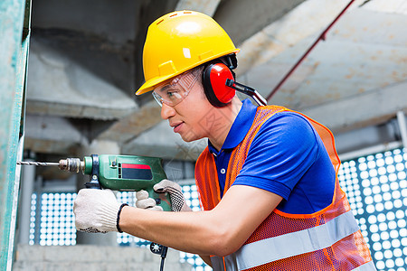 亚洲工人在建筑工地墙上钻井男性工作工具头盔钻孔房地产听力机器钻头职业图片