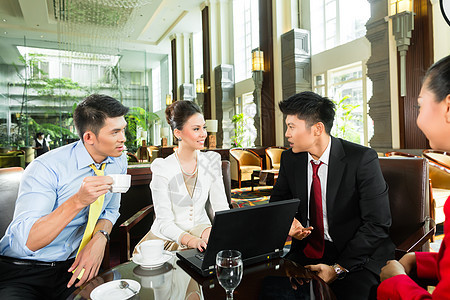 亚洲商界人士在酒店大厅开会时参加笔记本团体伙伴职业咖啡项目电脑房间会议合作图片