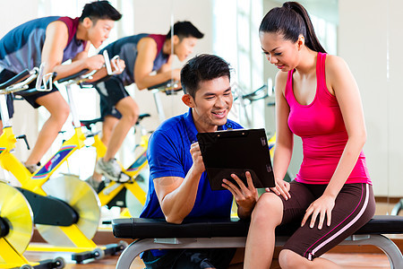 健身健身健身房妇女亚洲个人教练员工作私人培训师重量团体讨论女士男人自行车日程图片