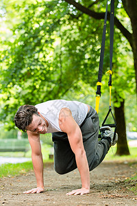 男子在城市公园做暂停训练教练运动健康身体吊带培训师男性磁带弹力耐力悬吊活动图片