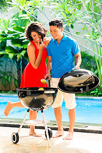 亚洲情侣在游泳池烧烤男人夫妻花园太阳团体女士树木水池玉米微笑图片