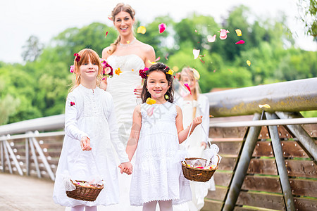 新娘穿着婚纱 与在桥上的伴娘结婚裙子女儿淋浴庆典篮子快乐花瓣女士新郎家庭图片