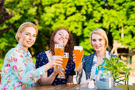 朋友们在花园酒吧喝啤酒眼镜饮料小麦玻璃女孩们花园乐趣啤酒友谊酒精图片