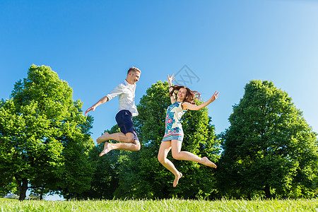 情侣在公园草坪上跳跃喜悦草地假期娱乐朋友们女士绿色友谊自由男人图片