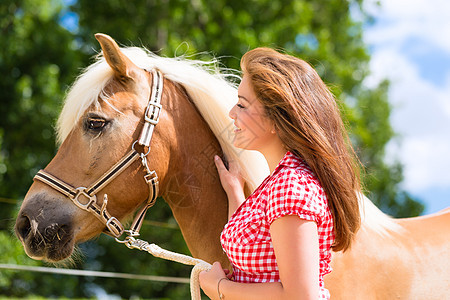 女人在小马农场上宠物马匹关爱国家乐趣马术女孩动物活动闲暇享受晴天图片